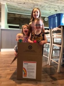 Four smiling kids standing in a delivery box